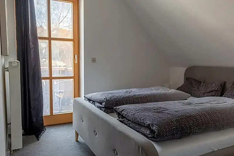 Hauptschlafzimmer mit Doppelbett und Tür zum Balkon